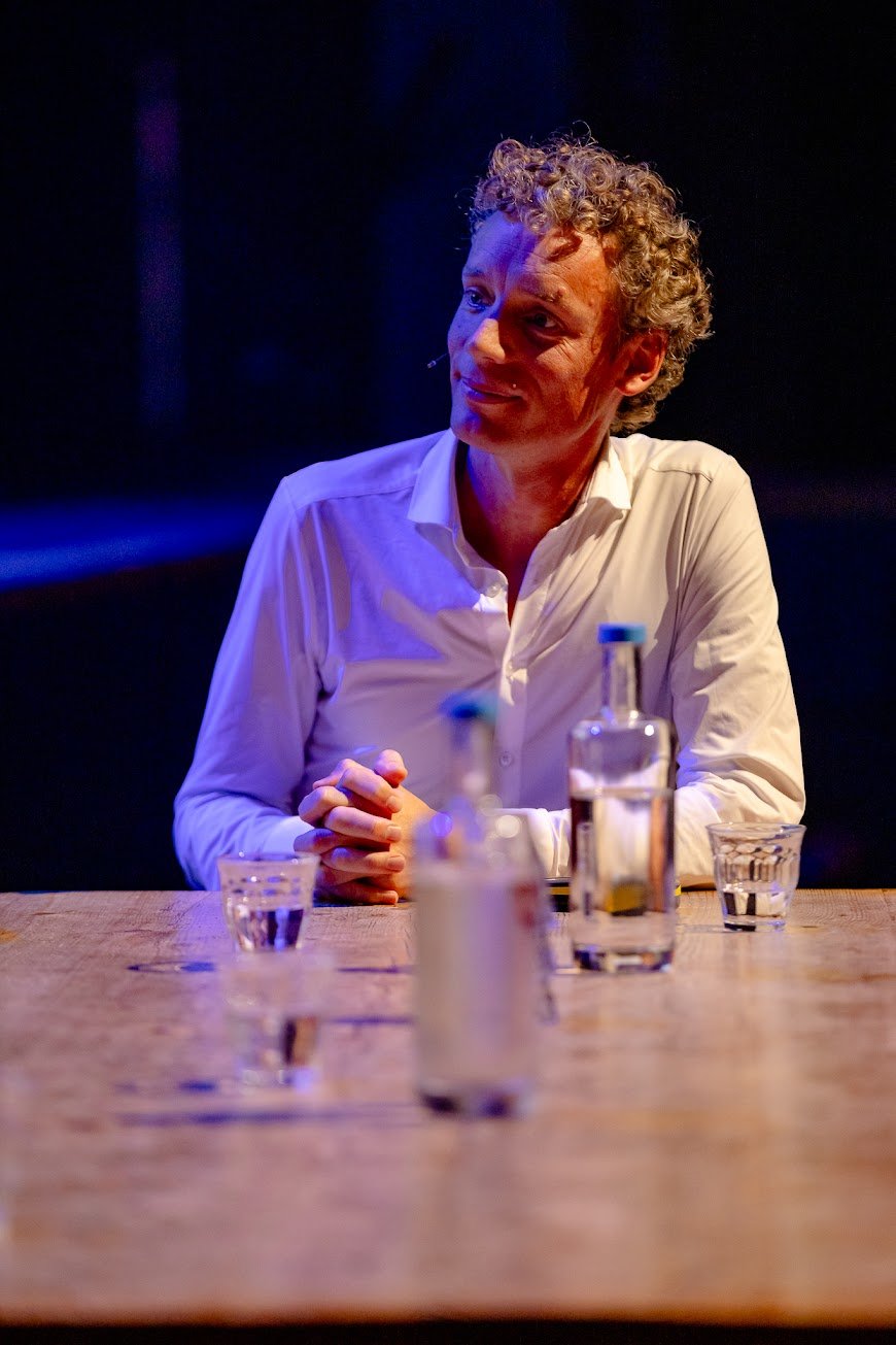 Staand portret van Laurens Waling aan de talkshowtafel, luisterend
