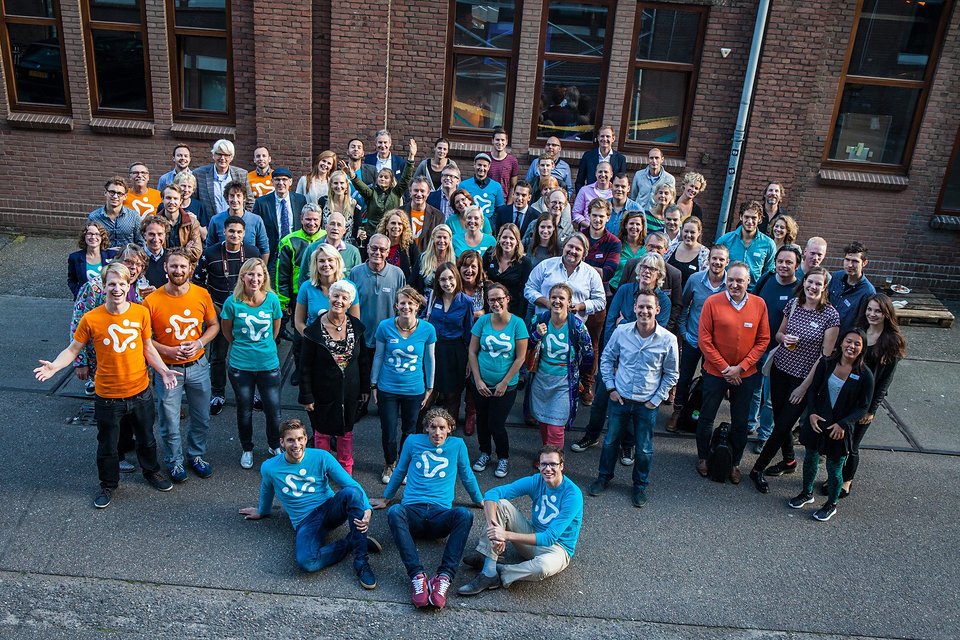 De Part-up-community poseert buiten voor een groepsfoto, velen in shirts met het Part-up-logo