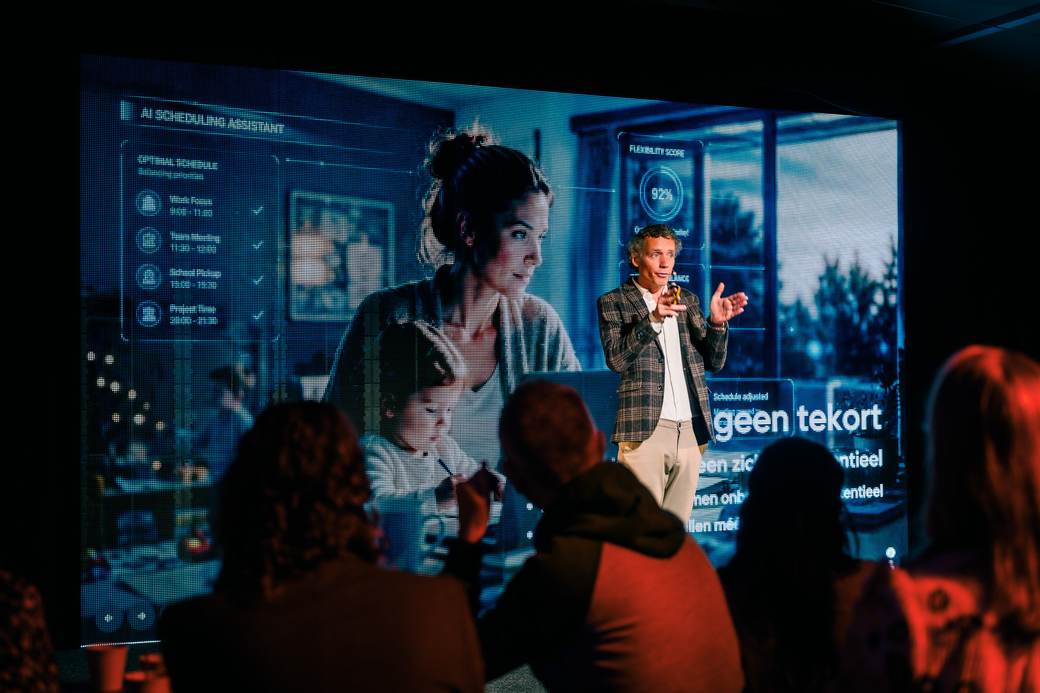 Laurens Waling addressing the room beside the screen with the AI scheduling assistant