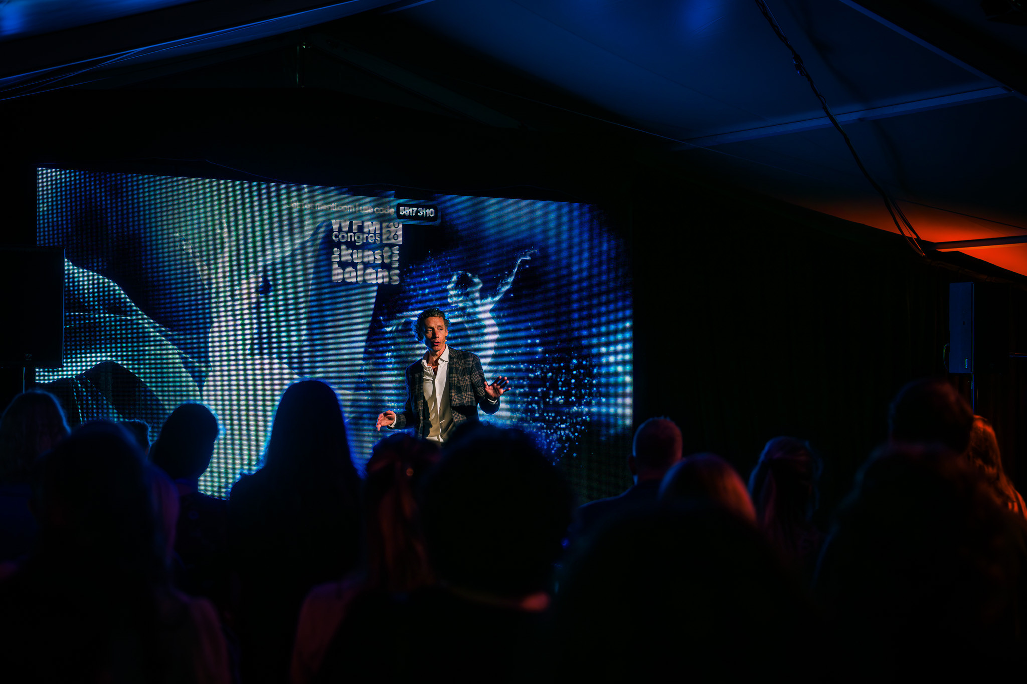 Laurens Waling on stage, small against a large screen with the audience in front