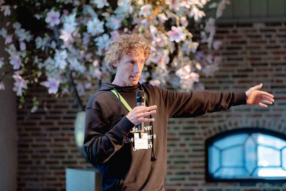 Laurens Waling explaining something with an outstretched arm, blossom in the foreground