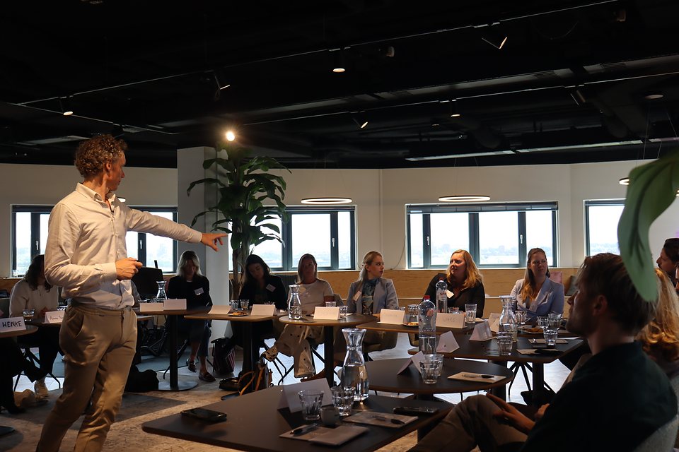 Laurens Waling leidt een werksessie met deelnemers aan lange tafels